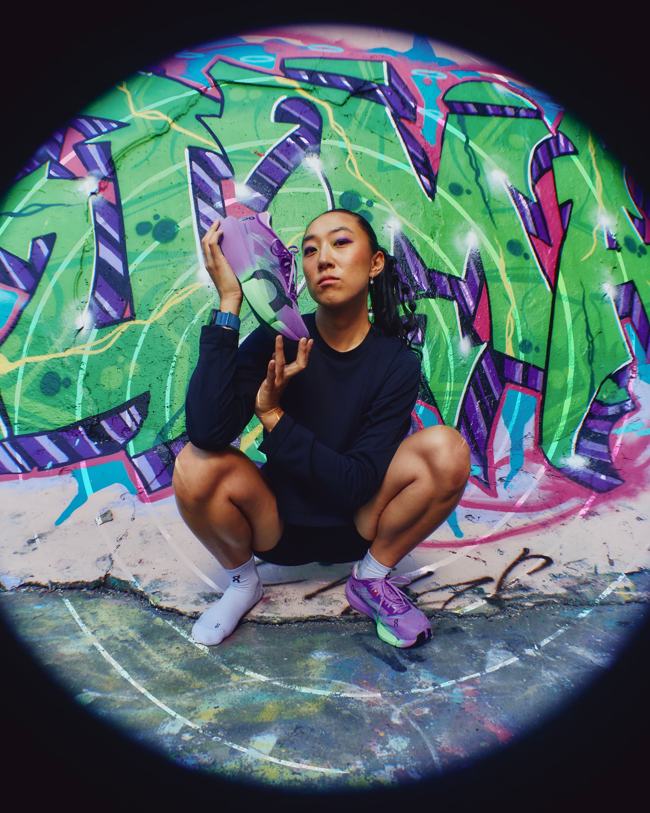 Runner holding the On Cloudboom Strike 2 against colourful graffiti